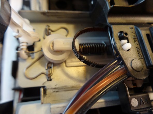 Using the spudger, press the spring section of the white pulley