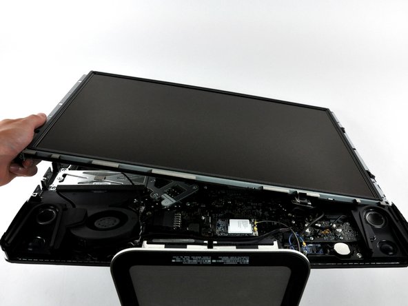 Image 2/2: Lift the display panel from its left edge and rotate it toward the right edge of the iMac.