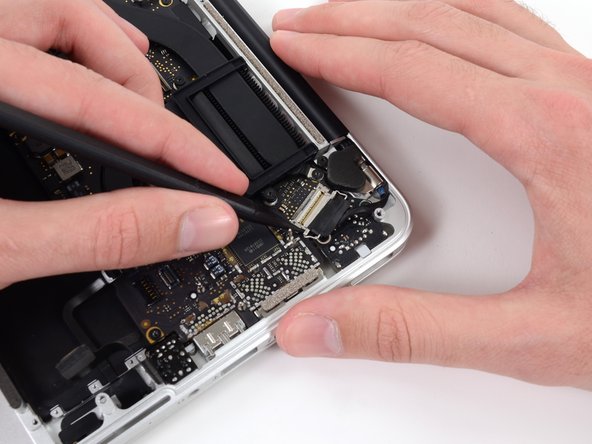 Image 2/3: Pull, but do not remove, the display data cable connector out of its socket and carefully move it out of the way.