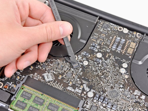 Image 1/3: It is useful to twist the spudger axially from beneath the fan cable wires to release the connector.