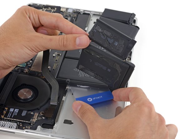 Holding the outer cells out of the way, insert the plastic card about halfway under the left center battery cell, avoiding the trackpad board.