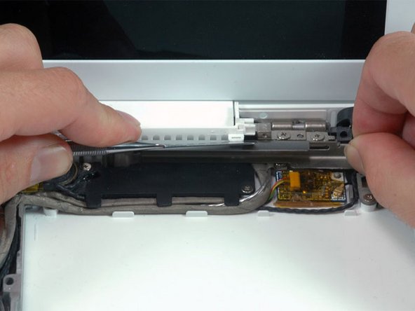 Using a spudger, gently pry up the white plastic slot and slide the metal c-channel to the right and away from the display.