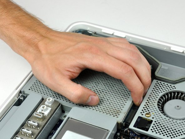 Image 1/3: Lift the free end of the optical drive just enough to clear the fan cover.  Lifting the free end of the optical drive too far may break the plastic positioning pins off the front bezel.