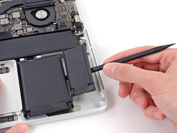 Image 2/2: Run the spudger down along the right side of the larger right battery cell.
