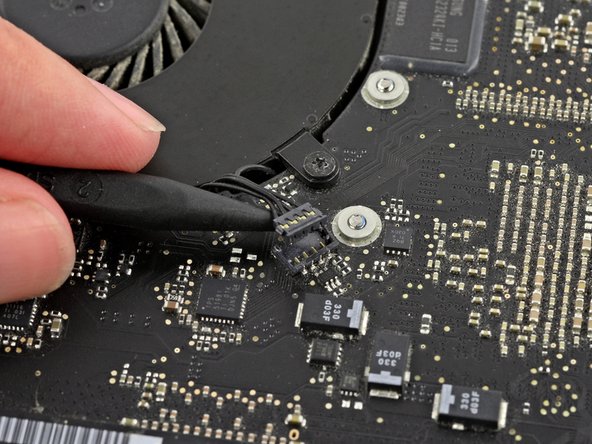 Image 2/3: It is useful to twist the spudger axially from beneath the fan cable wires to release the connector.