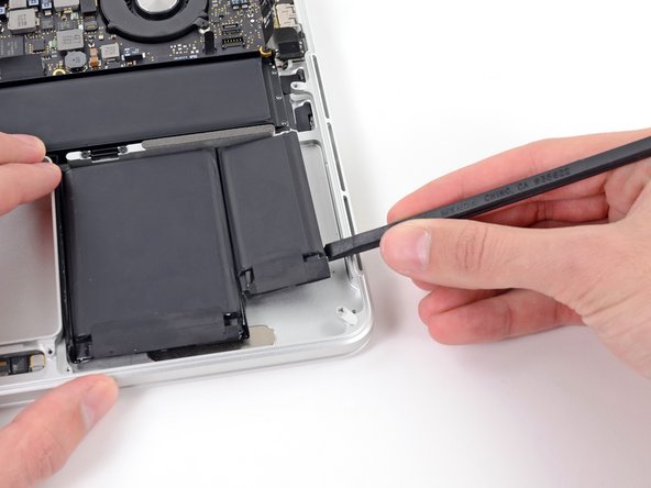 Image 1/2: Run the spudger up along the right side of the rightmost battery cell to release the adhesive.