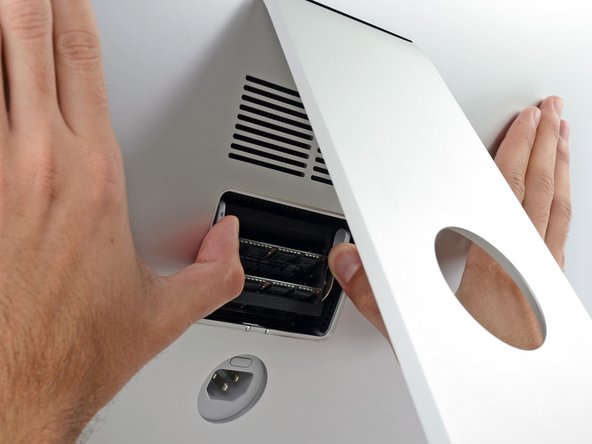 Image 2/3: Pull the tabs out and down, swinging the RAM tray down to a near-horizontal position.