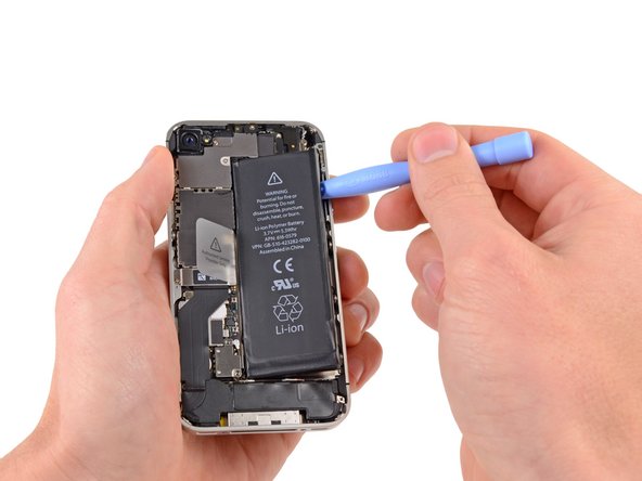 Run the plastic opening tool along the right edge of the battery and pry up at several points to completely separate it from the adhesive securing it to the outer case.