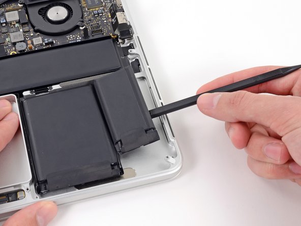 Image 1/3: Carefully wedge the spudger inwards, being careful to not damage the battery cells.