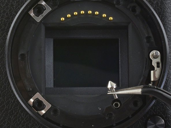 Use tweezers to lift the pyramid screw and spring from the lens assembly.