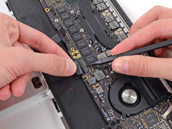 Image 2/3: Grasp the plastic pull tab and pull the keyboard ribbon cable out of its socket.