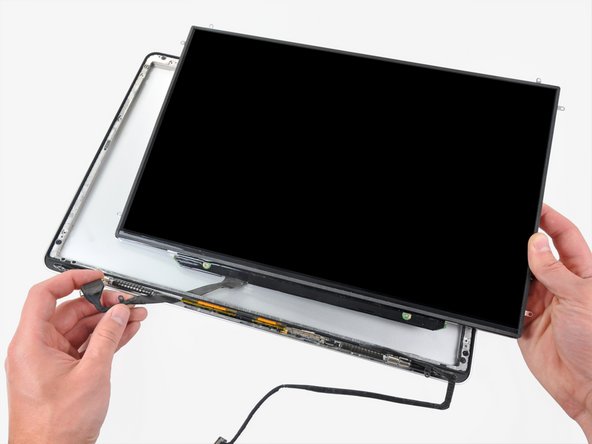 Image 1/1: It may be helpful to use one hand to feed the display data cable through its channel in the aluminum display assembly as you pull the LCD toward the top edge of the display with the other hand.