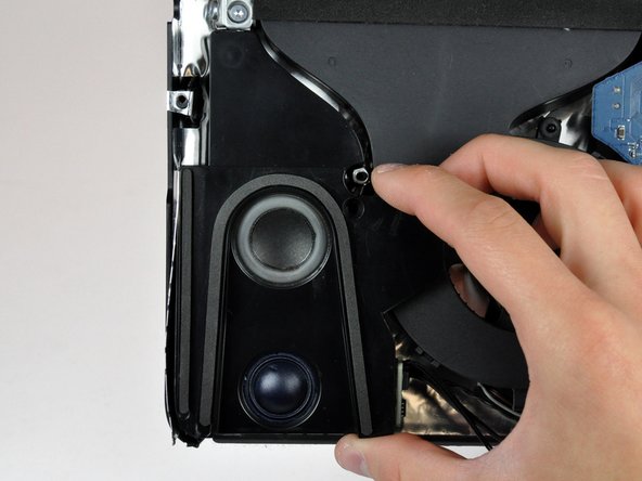 Image 2/2: Lift the left speaker up and out of the rear case. Don't try to slide the speaker out, since there is a plastic mounting pin under the top end of the speaker housing that holds it in place.