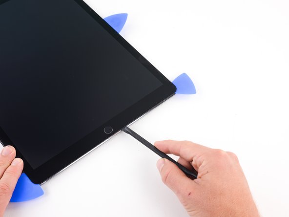Slide the halberd spudger along the lower edge of the iPad stopping  short about 1 centimeter before reaching the home button.