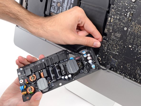 Image 1/2: Flip the top of the power supply towards you to access the DC power cable connection behind the logic board.