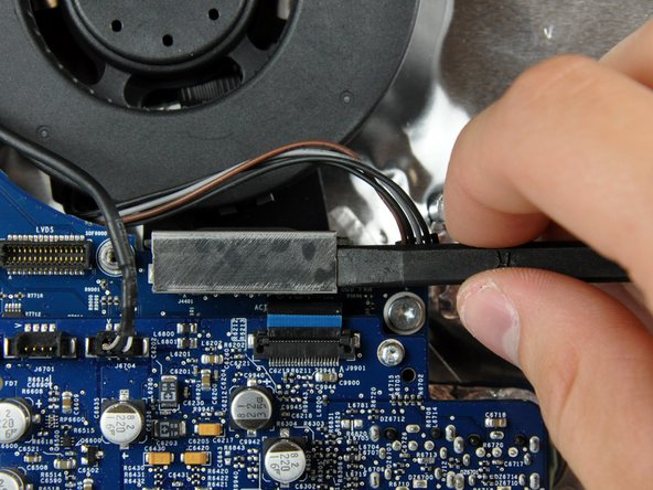 Image 1/2: Lift the optical drive cable clip off the logic board.