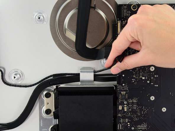 Image 1/3: In a similar fashion, lift the combo SATA data/power cable up out of the retaining clip.